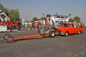 Historic, classic Top Fuel Dragsters are push-started down the return road in front of the cheering spectators.